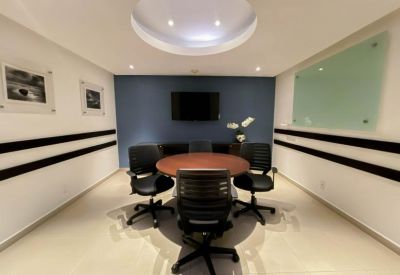 Modern conference room featuring a round wooden table, black ergonomic chairs, and a blue feature wall.