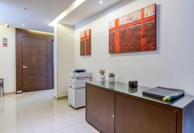 Office corridor featuring abstract red paintings and a wooden storage credenza.