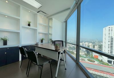 Private office with a corner window overlooking the city skyline and built-in white shelving.