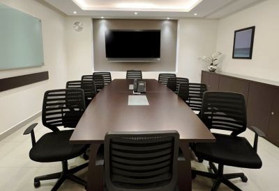 Professional boardroom with a long dark wood table and black ergonomic chairs.