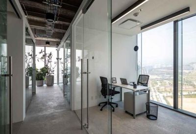 Private glass-walled office with a desk and city views.