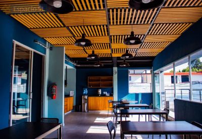 Communal break area with wooden slatted ceilings, hanging pendant lights, and several dining tables.
