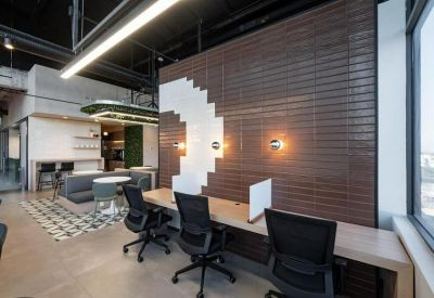 Open-plan office with desks against a dark brick feature wall and white geometric tile accents.