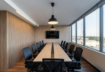 Sleek boardroom with a long wooden table, black chairs, and pendant lighting.
