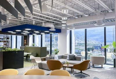 Vibrant communal workspace with yellow chairs, a blue ceiling feature, and city views.