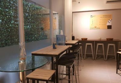 Shared break area with high tables, bar stools, and views of lush greenery.