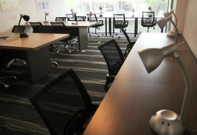Spacious open-plan workspace featuring multiple desks with ergonomic chairs and lamps.