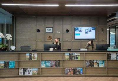 Sleek wooden reception desk with built-in bookshelves and digital displays.