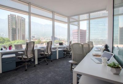 Professional row of desks in a bright office with floor-to-ceiling windows showing mountains.