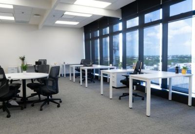 Open-plan coworking area with a round collaboration table and floor-to-ceiling windows.