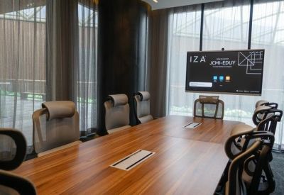 Meeting room with a wooden table and a wall-mounted digital screen for presentations.