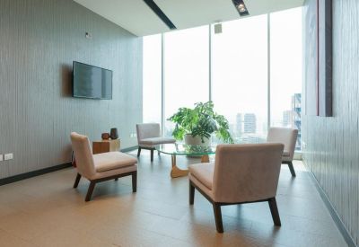 Lounge area with chairs and large windows offering city views.
