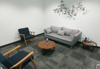 Cozy lounge area with a gray sofa, blue armchairs, and a round coffee table.