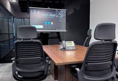 Small meeting room with a wooden table, conference phone, and digital screen.