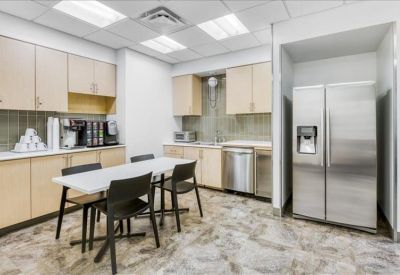 Modern communal kitchen and dining area with stainless steel fridge and coffee station.