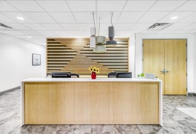 Bright reception desk with light wood paneling, hanging lights, and a decorative slatted wall.