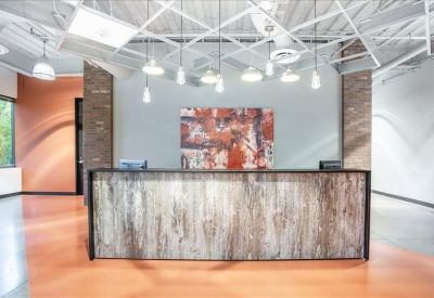 Modern reception desk with a wood-texture front and colorful abstract artwork behind it.