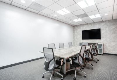 Professional meeting room with a long wooden table, ergonomic chairs, and wall-mounted TV.