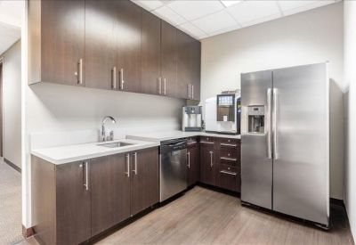 Modern communal kitchen with dark wood cabinets and stainless steel appliances.