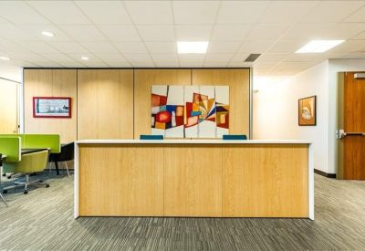 Wooden reception desk in a well-lit lobby with colorful abstract art.