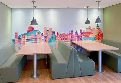 Coworking area featuring green padded booth seating and a colorful city mural.