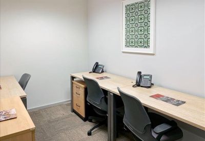 Bright, white office room featuring two desks with landline phones and a framed green print.