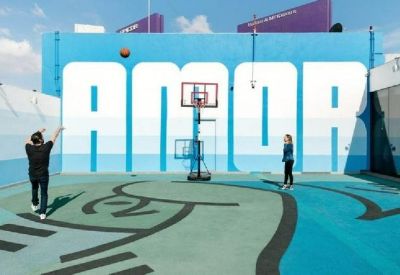 Outdoor basketball court with large mural saying 'AMOR'.