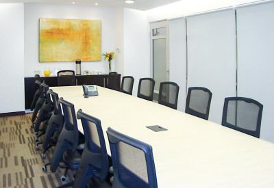 Long boardroom table with black mesh chairs and yellow abstract art.