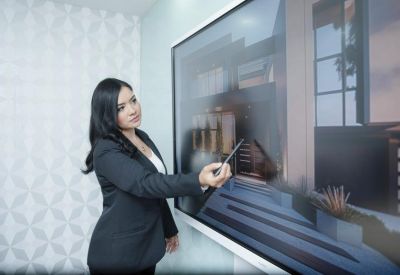 Presenter pointing at a screen showing a building design during a meeting.