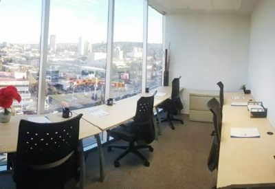 Bright coworking area with window-facing desks and city skyline views.