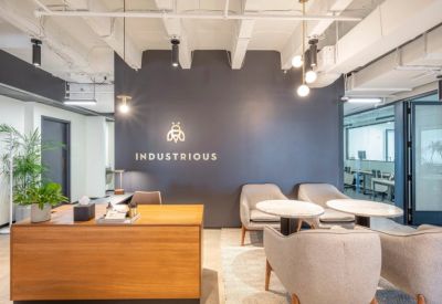 Modern reception desk made of wood with grey seating and a branded wall.