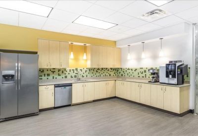 Modern kitchen and break area with light wood cabinetry and a vibrant patterned backsplash.
