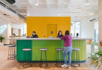Vibrant reception desk with a textured green front and a bright yellow feature wall behind it.