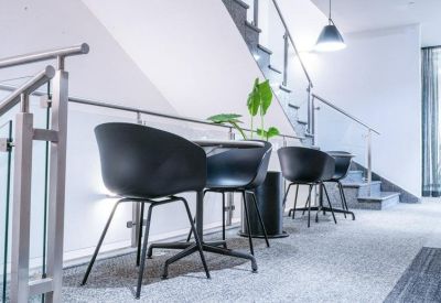 Breakout area with black bucket chairs and a glass-paneled staircase.