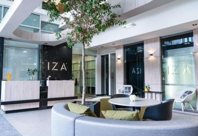 Modern lobby and reception area with a tall indoor tree and marble branding wall.