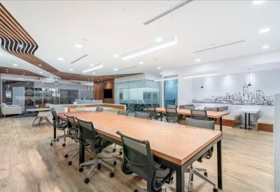 Long wooden communal table in a modern coworking space with unique slatted ceiling accents.