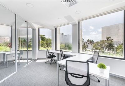 Bright private office suite with large windows overlooking trees and city buildings.