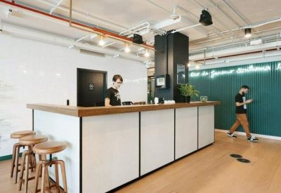 Reception area featuring a white desk, wooden stools, and a green accent wall with neon lighting.