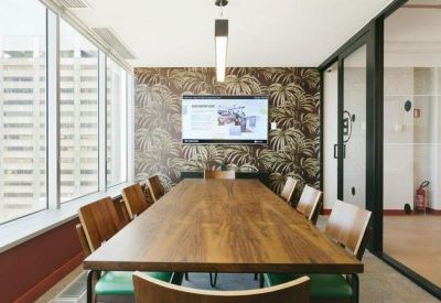 Professional meeting room with a long wooden table, leather chairs, and a tropical leaf print feature wall.