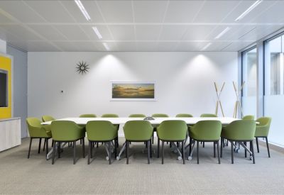 Large meeting room featuring a long white table and vibrant lime green chairs.
