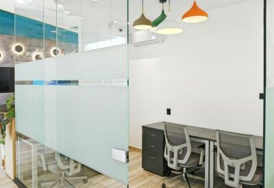 Compact two-person office with frosted glass partitions and colorful hanging pendant lamps.