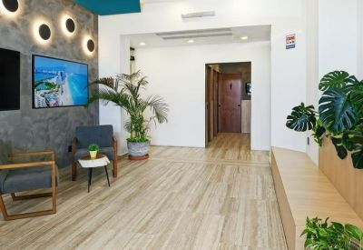 Reception area with a textured gray feature wall, accent lighting, and potted plants.