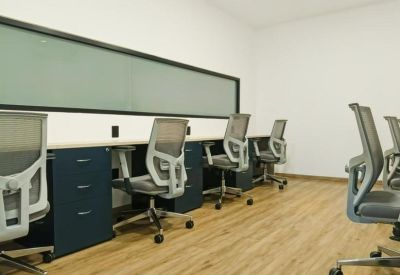 Shared workspace with blue cabinetry, gray mesh chairs, and warm wood flooring.