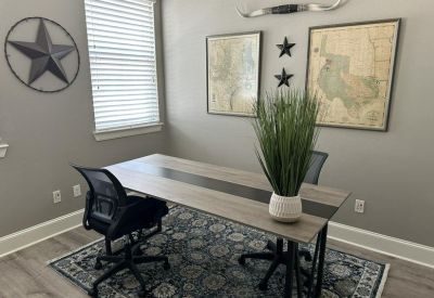 Office space decorated with a Texas theme, featuring maps, a longhorn mount, and a patterned rug.