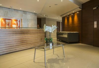 Sleek professional reception area featuring a wood-paneled desk, glass coffee table, and white orchid.