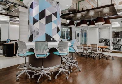A breakout area featuring high-top stools and a tall pillar with a blue and grey geometric pattern.