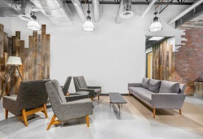 Cozy communal lounge with grey sofas, armchairs, and rustic wood-paneled walls.