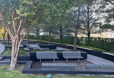 Lush outdoor communal terrace with modern metal benches and green trees.