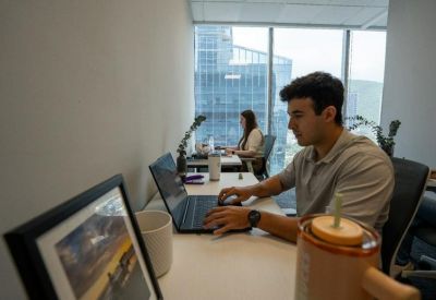 Close-up of a professional at a desk with a laptop and a view of the city.
