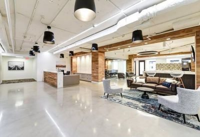 Spacious communal lounge with leather sofas, grey armchairs, and warm wood wall accents.